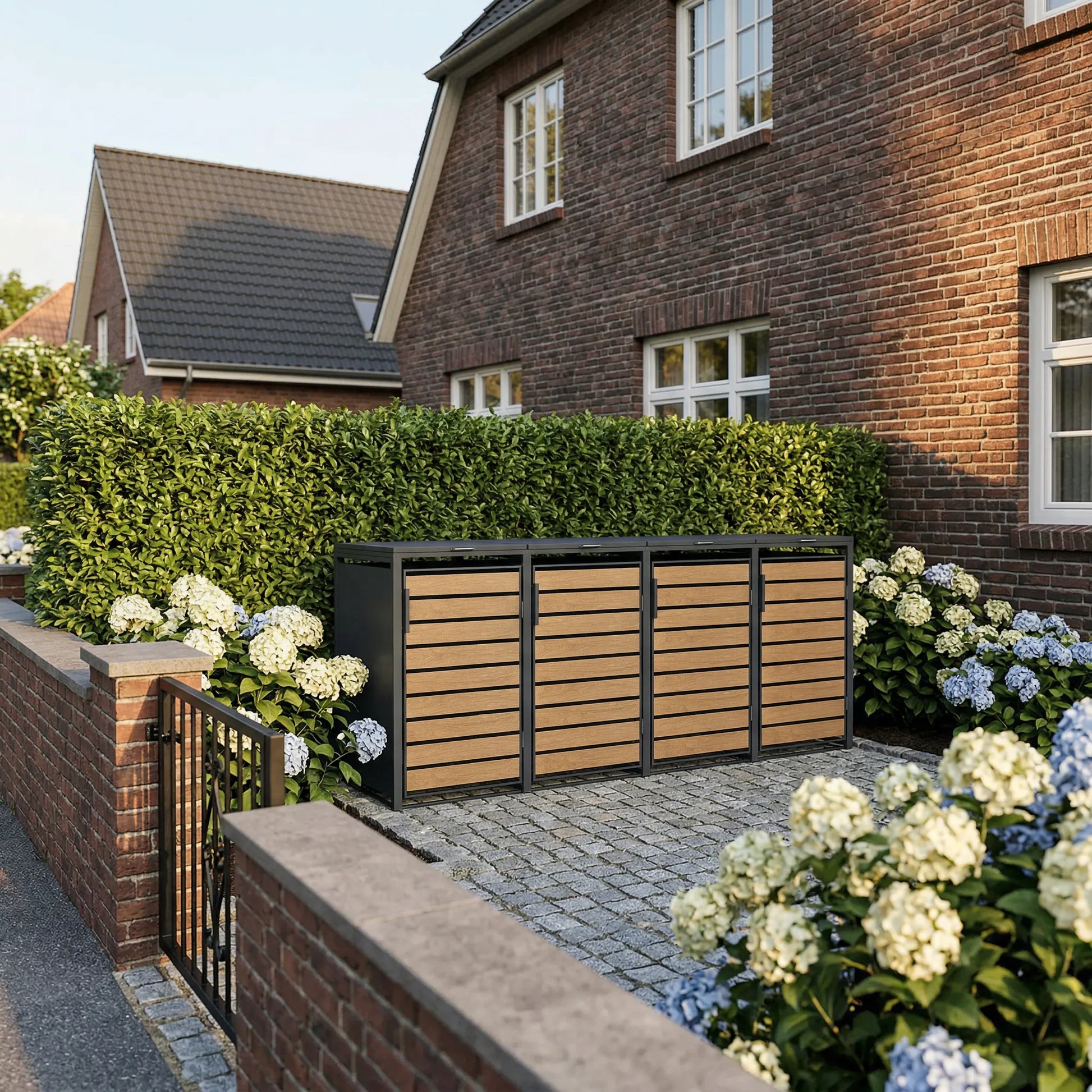 Mülltonnenbox 4er Holzoptik hinter Klinkermauer – hohe Hecke und weiße Hortensien im Vorgarten