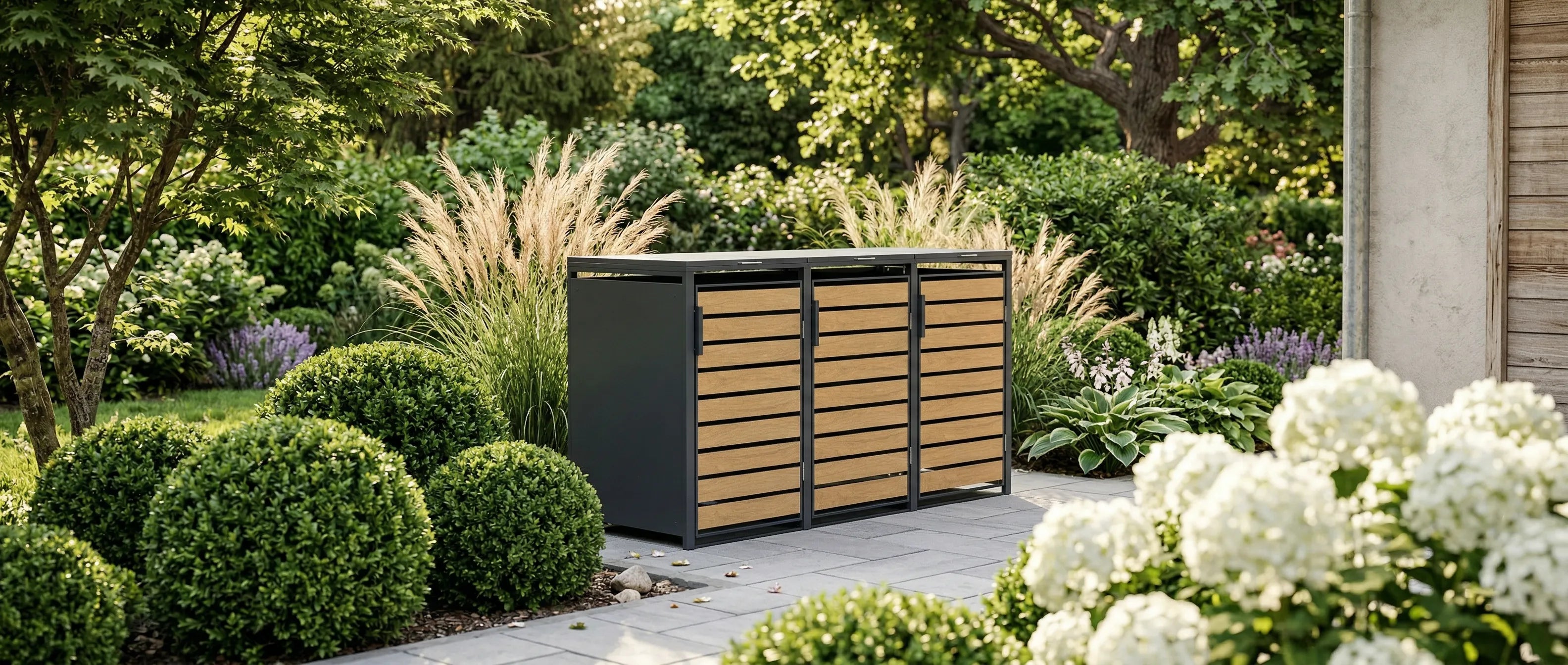 Mülltonnenbox Holzoptik im grünen Garten – TREVANO 3er Box mit Buchskugeln und Hortensien